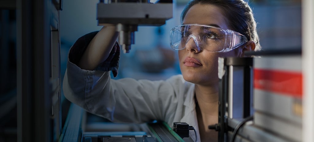 Engenheiro trabalha em fábrica com cobots industriais.